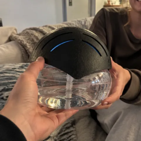 Hands holding the TwistaPure water air purifier with water in the clear bowl